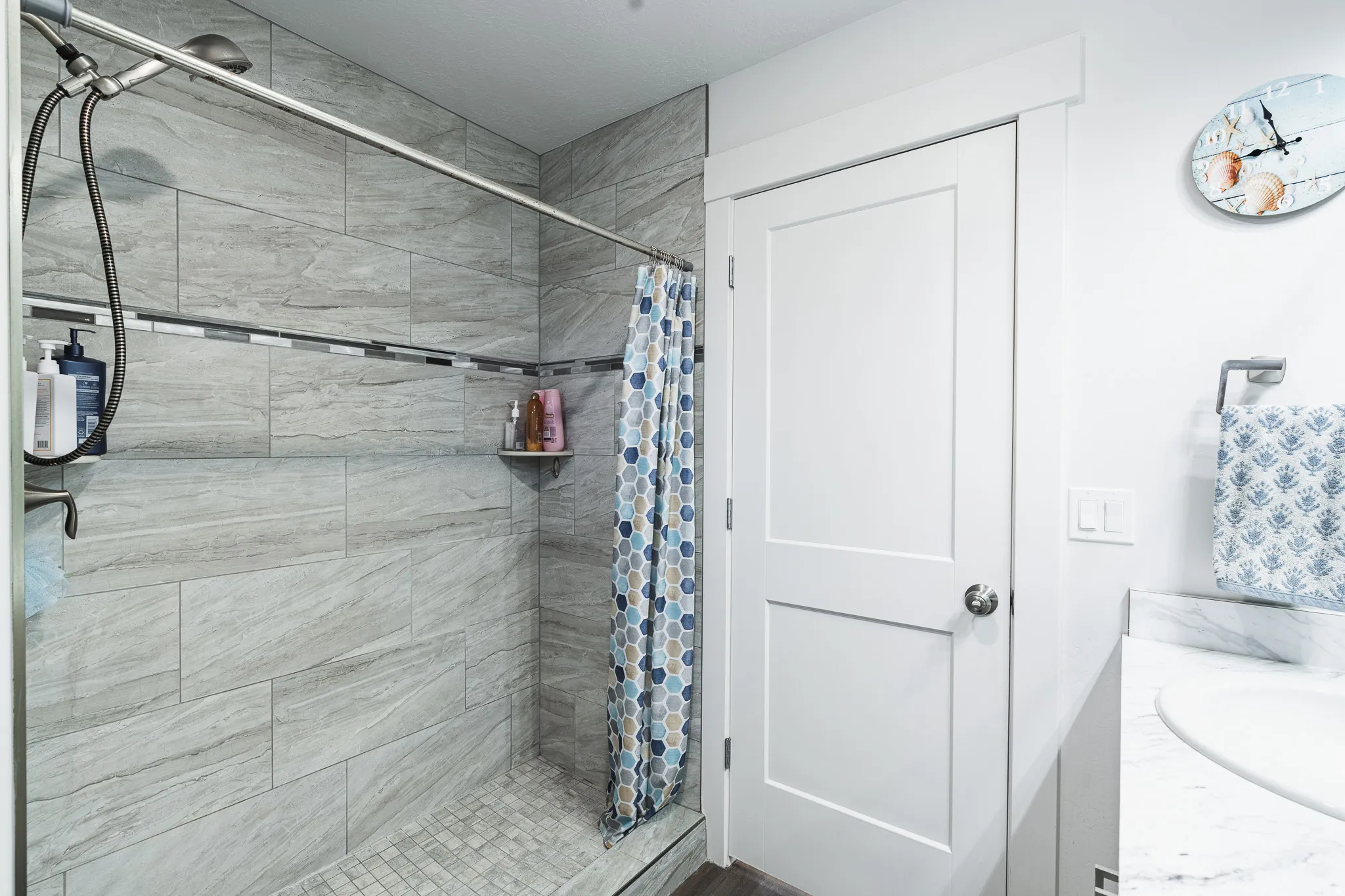 Shower with large format tile surround, mosaic accent band, and built-in corner shelf