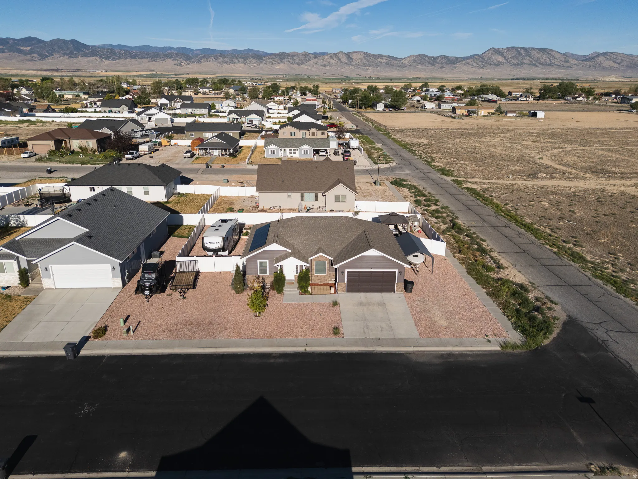Ranch-style residence featuring a prominent front-facing garage, gravel landscaping, and a fenced side yard