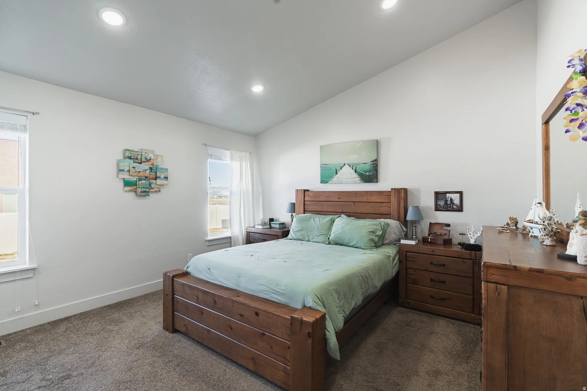 Spacious room featuring vaulted ceilings, recessed lighting, two windows with white trim, and light-toned wall paint