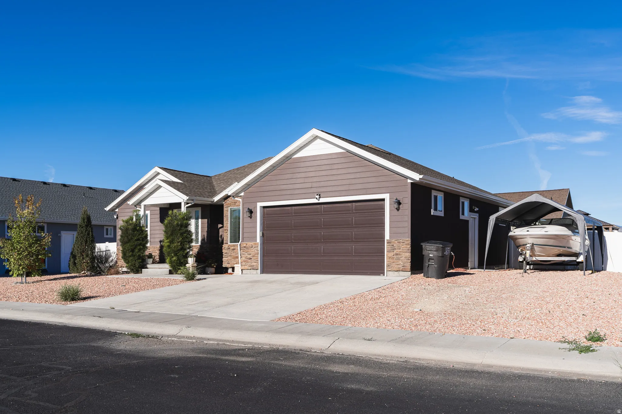 Ranch-style exterior with brown siding, an attached two-car garage, and a concrete driveway