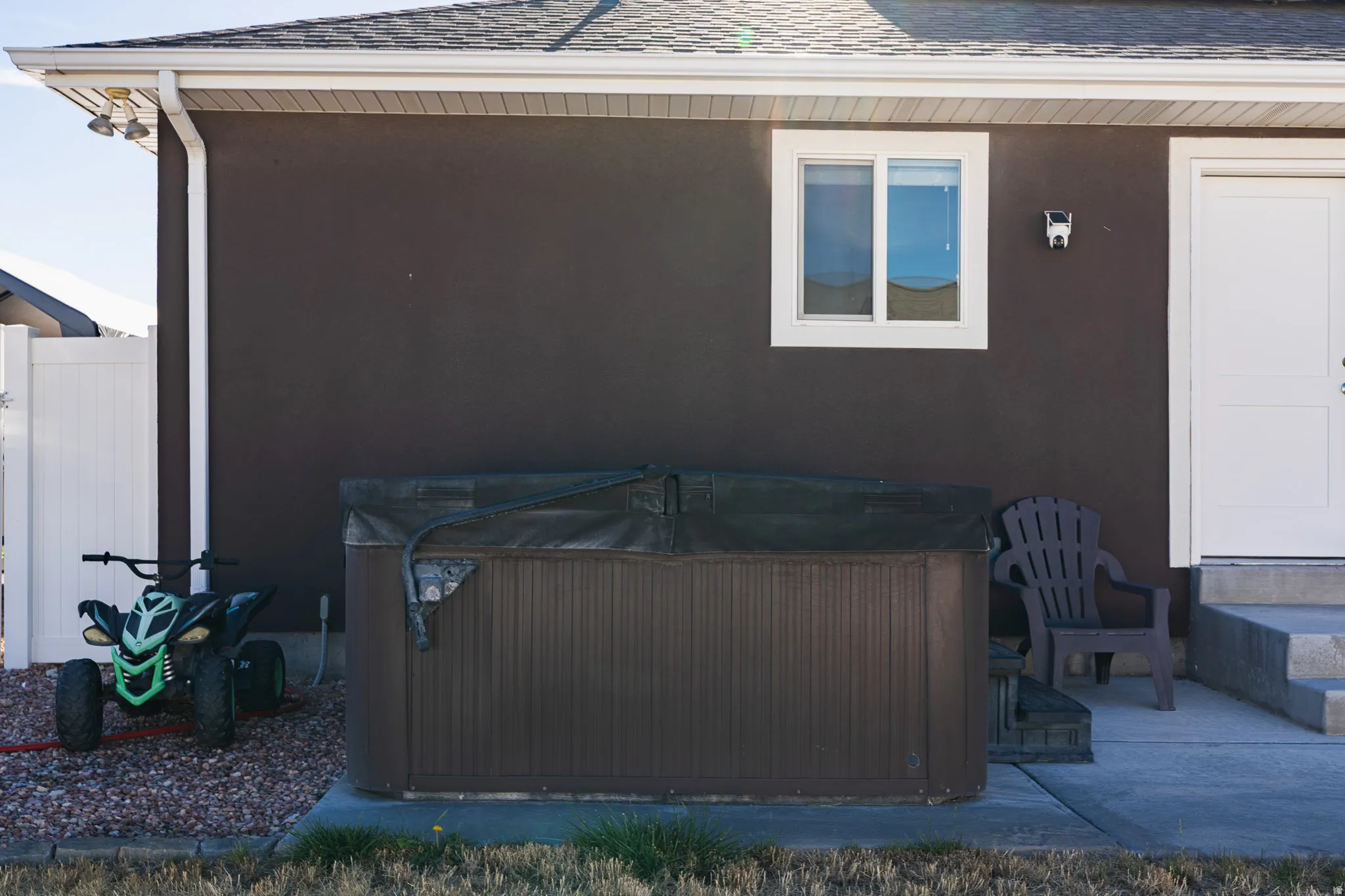 Exterior hot tub, white window trim, white door, concrete steps, and white vinyl fencing