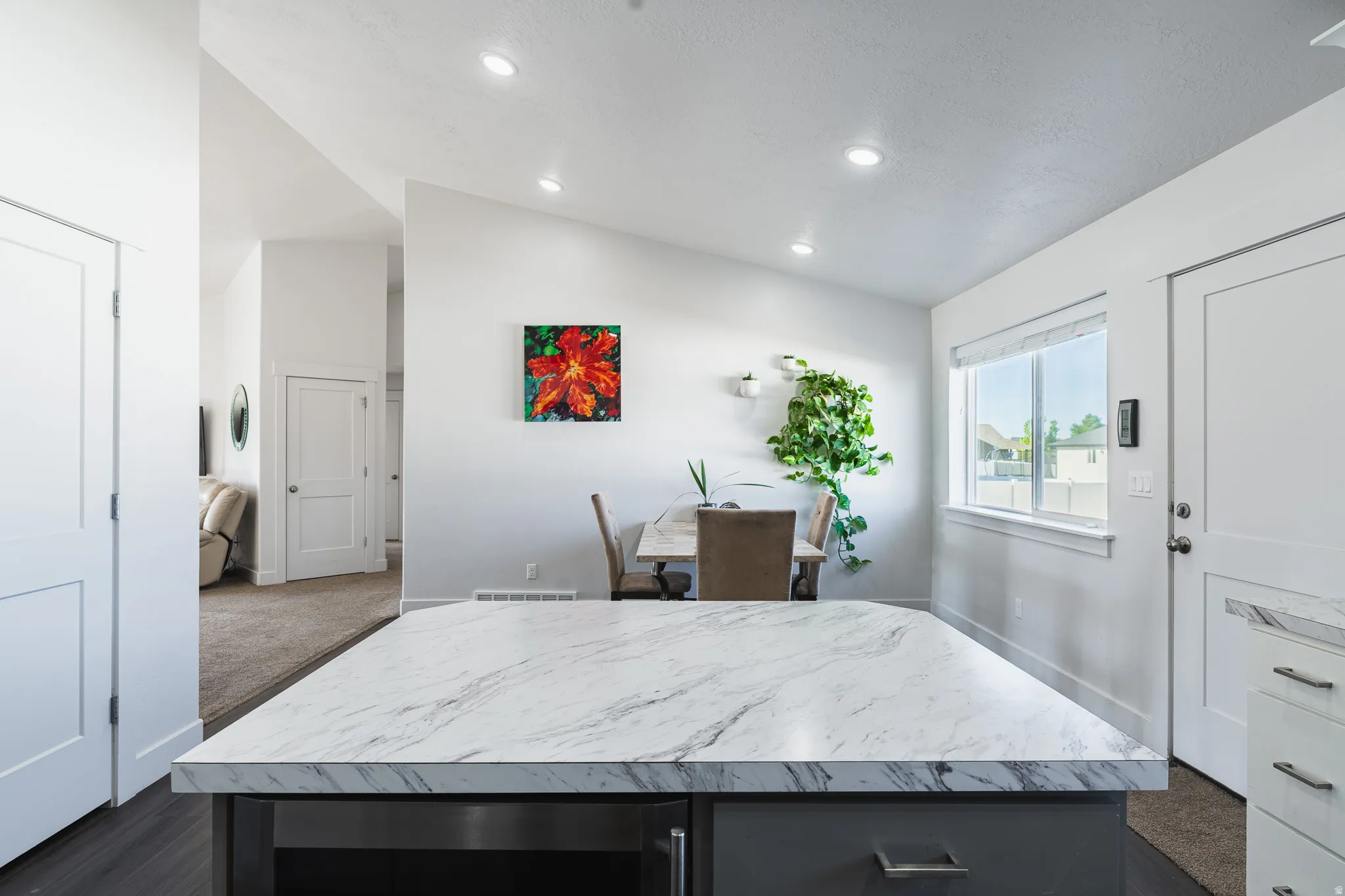 Kitchen island with a marble-finish countertop, dark cabinetry, and integrated appliance