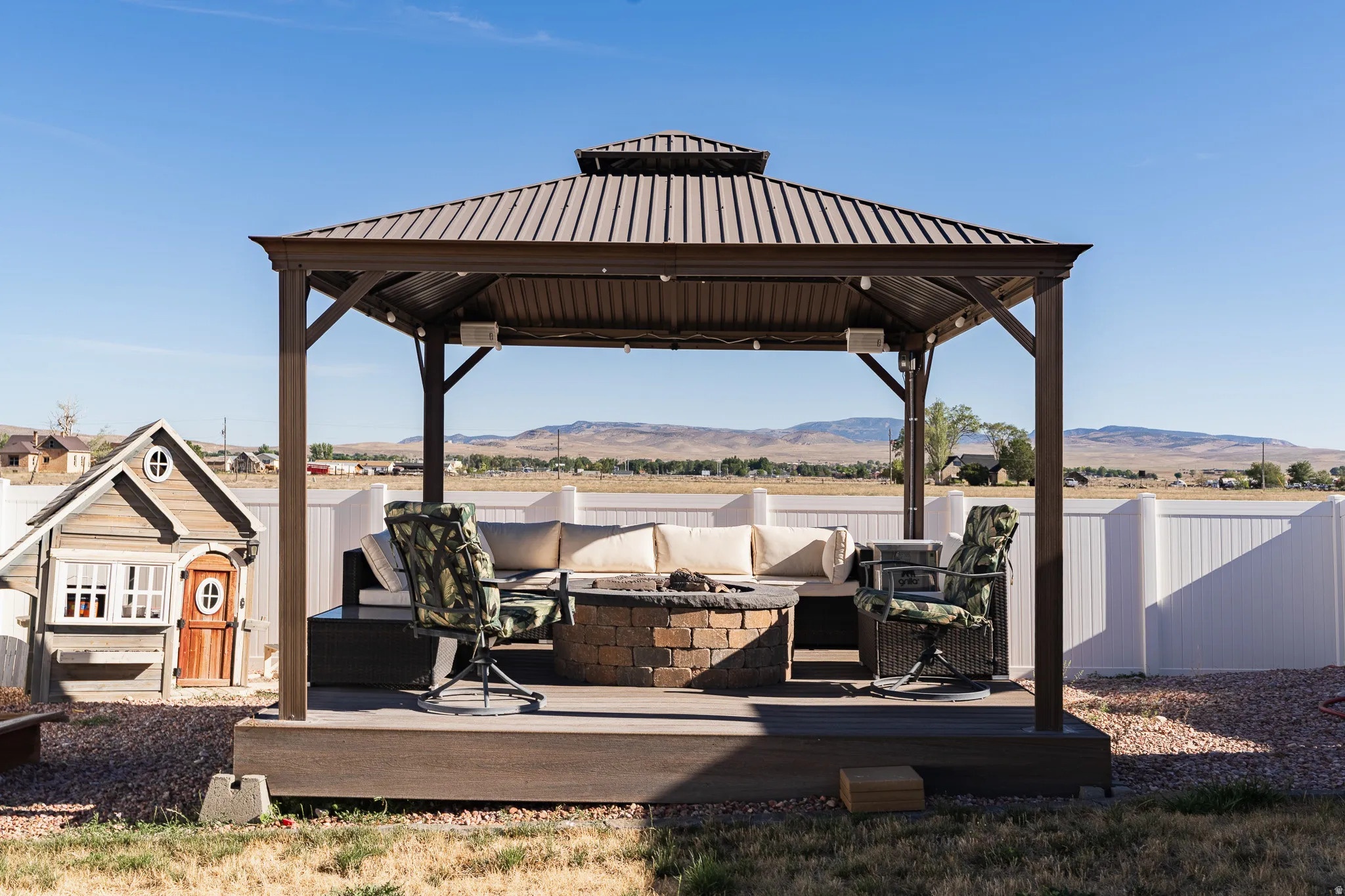 Outdoor gazebo with a tiered metal roof, a built-in fire pit, and a raised composite deck