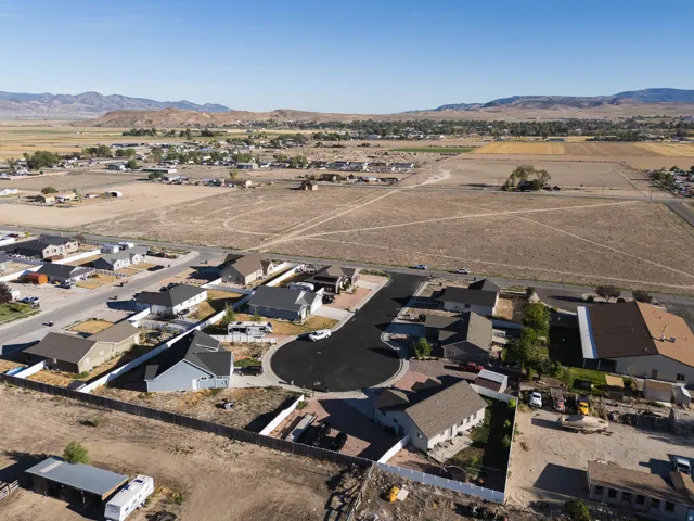 Cul-de-sac street with single-story residences, surrounded by open land and distant mountains