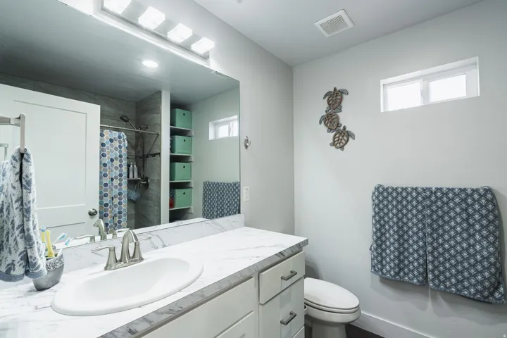 Bathroom featuring a large vanity mirror, white cabinetry with brushed nickel hardware, an undermount sink, and a light-colored countertop
