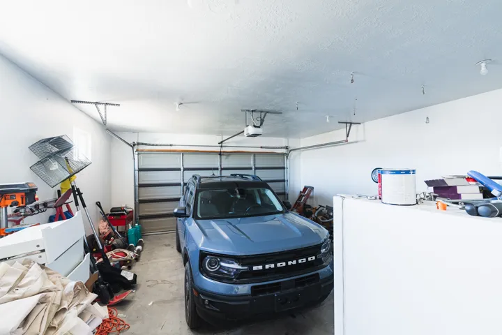 Attached garage with a roll-up door, integrated automatic opener, and overhead lighting