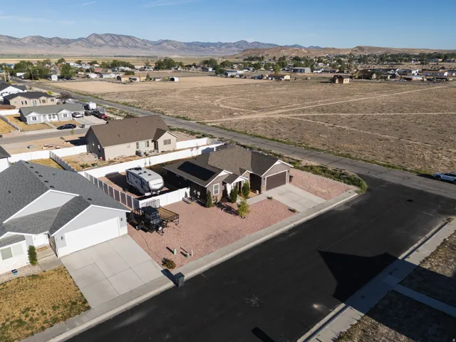 Single-story residence with an attached garage, paved driveway, and solar panels
