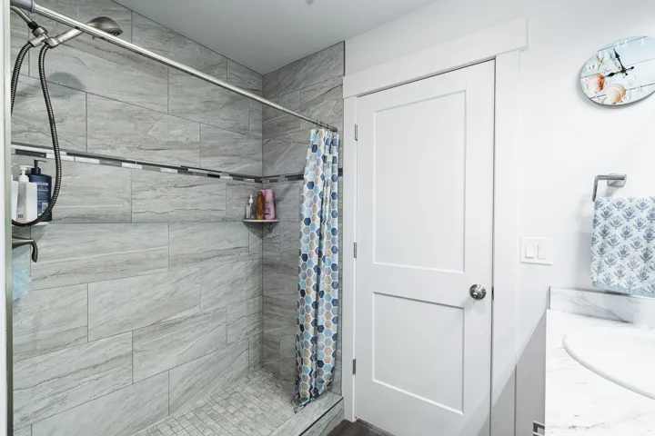 Shower with large format tile surround, mosaic accent band, and built-in corner shelf