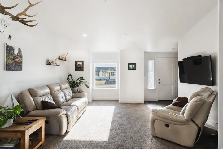 Recessed lighting, large window, neutral wall paint, white trim, and gray carpet