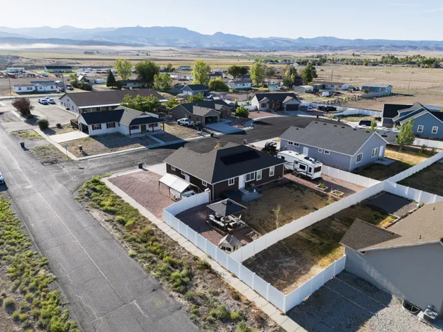 Expansive property featuring a gravel yard, white privacy fencing, and a covered patio area