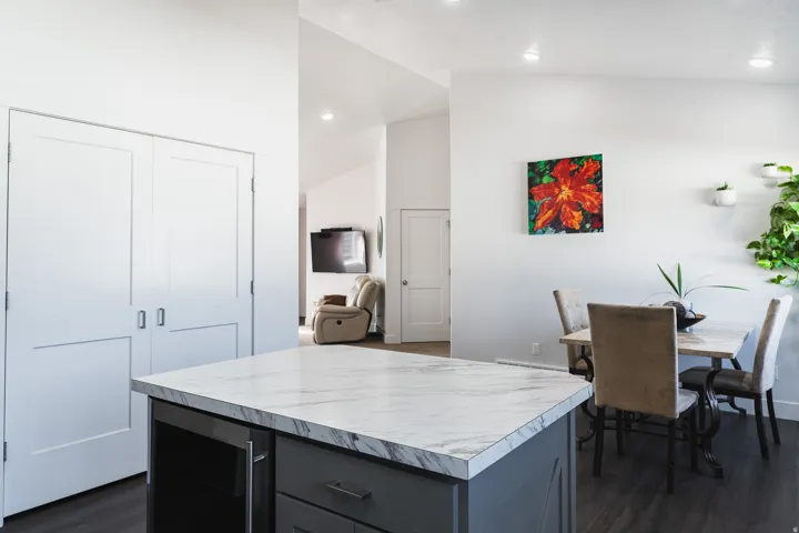 Kitchen island with a marbled countertop, dark gray cabinetry, and integrated appliances
