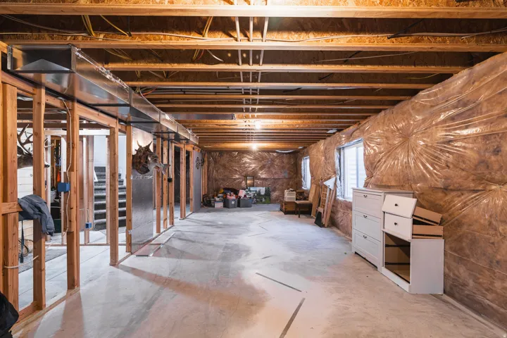 Unfinished lower level with concrete flooring, exposed wood framing, and multiple windows