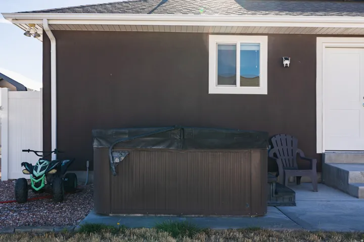 Exterior hot tub, white window trim, white door, concrete steps, and white vinyl fencing
