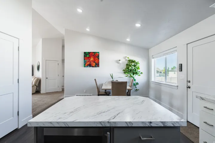 Kitchen island with a marble-finish countertop, dark cabinetry, and integrated appliance