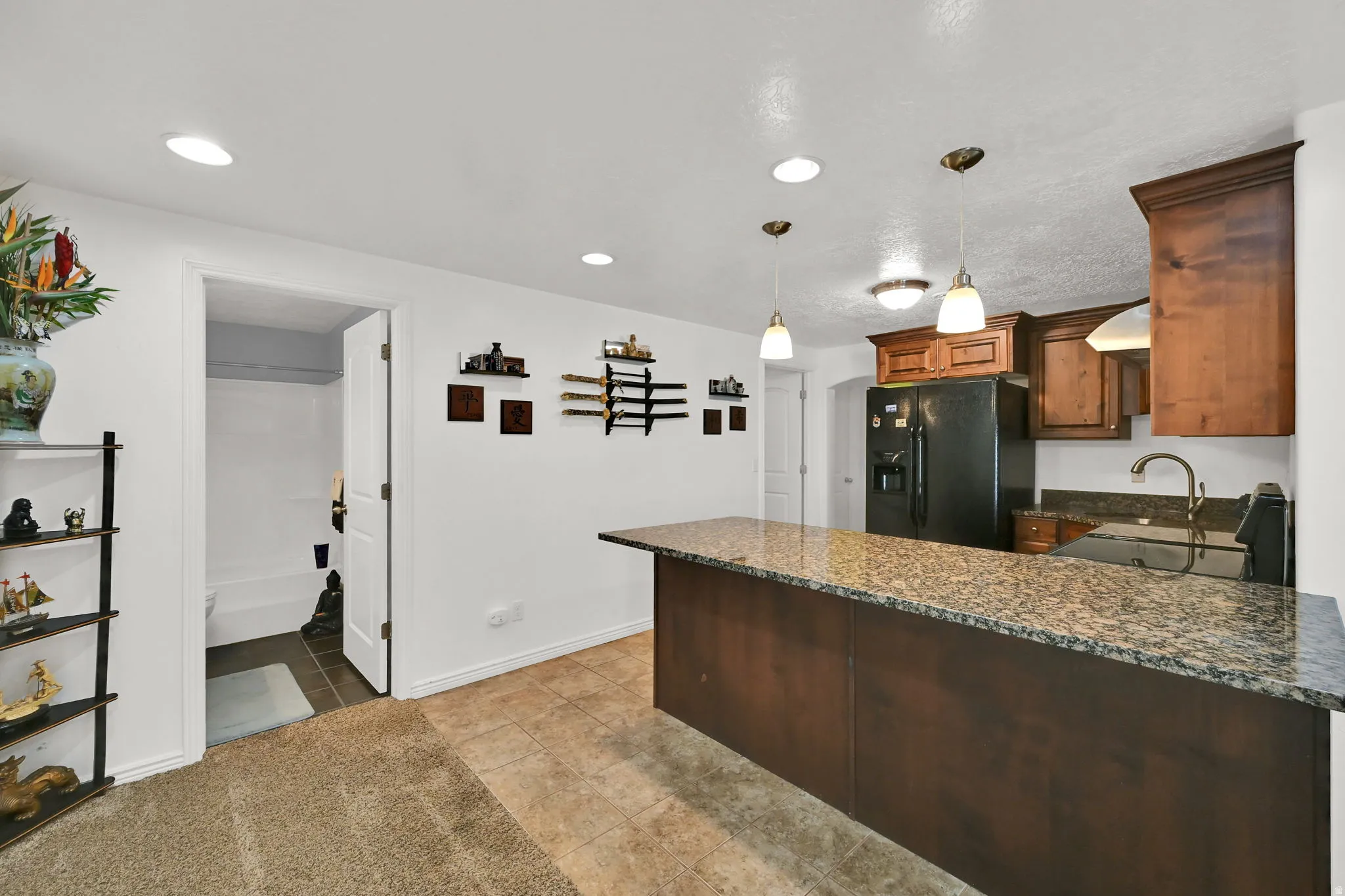 BASEMENT Kitchenette featuring a granite countertop island, dark wood-finish cabinetry, recessed lighting, and pendant light fixtures