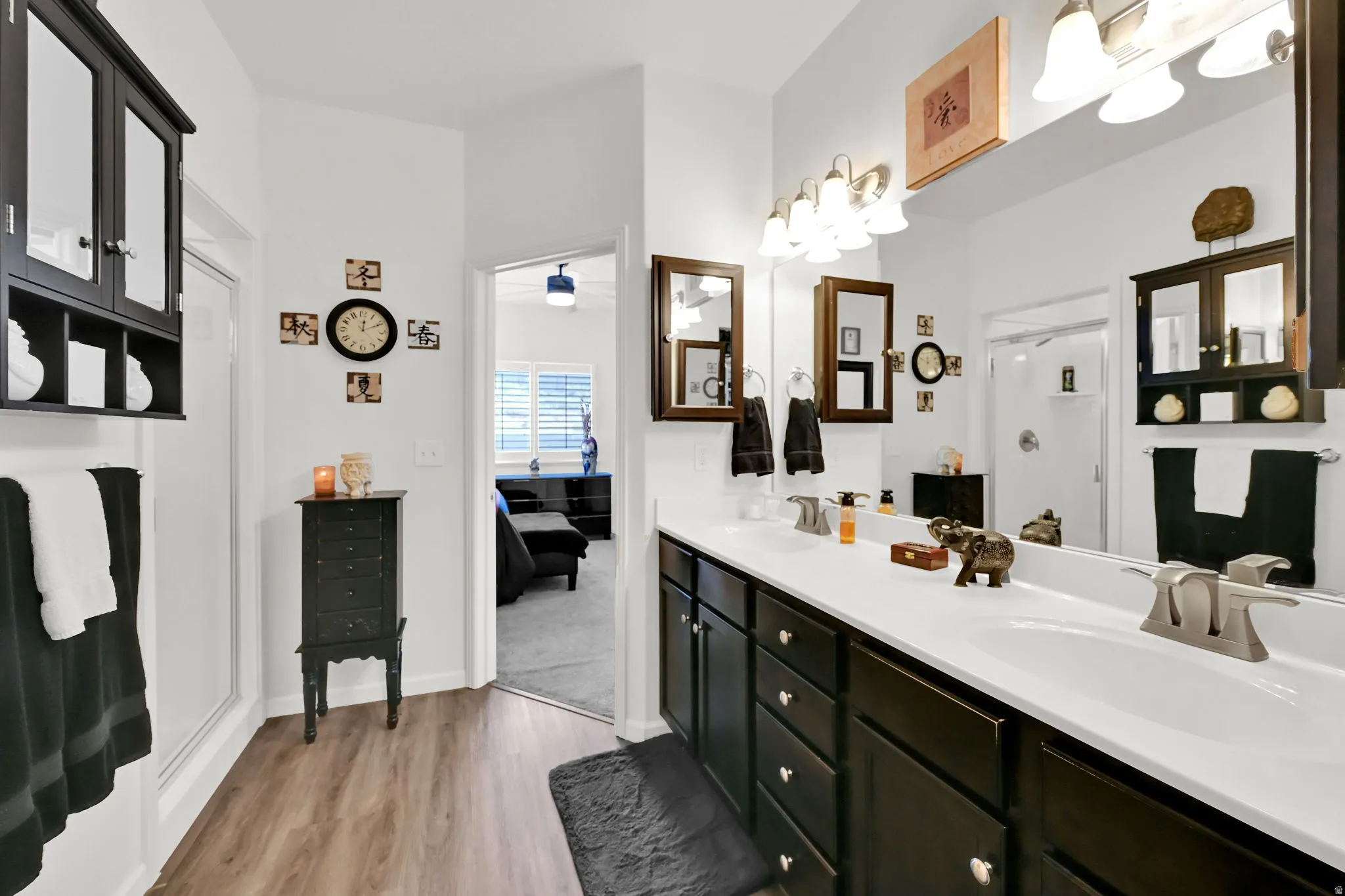 MASTER BATHROOM. Dual vanity with white countertops, dark wood-finish cabinetry, and wood-finish flooring