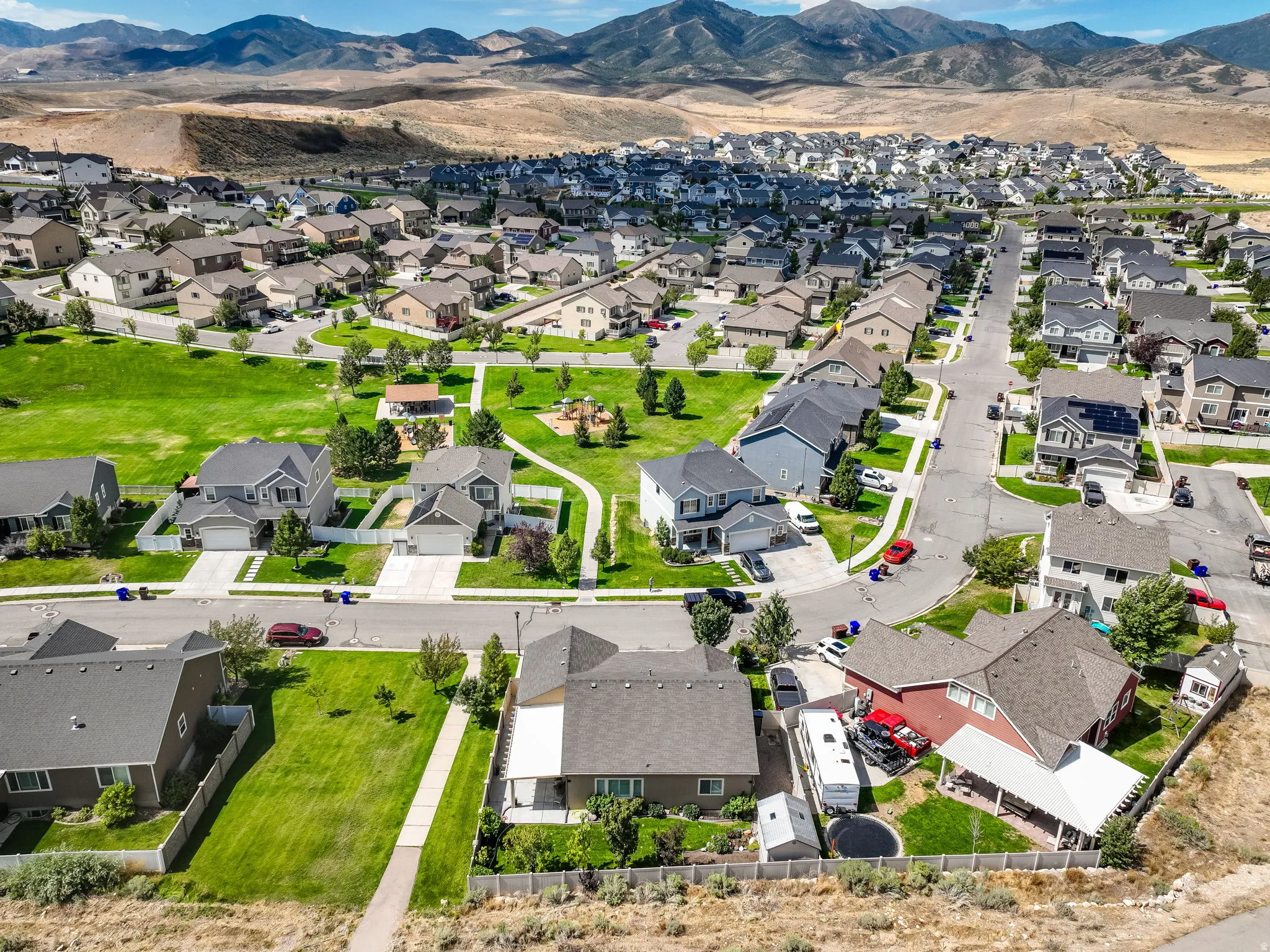 Residential development with a central green space, paved streets, and distant mountain scenery