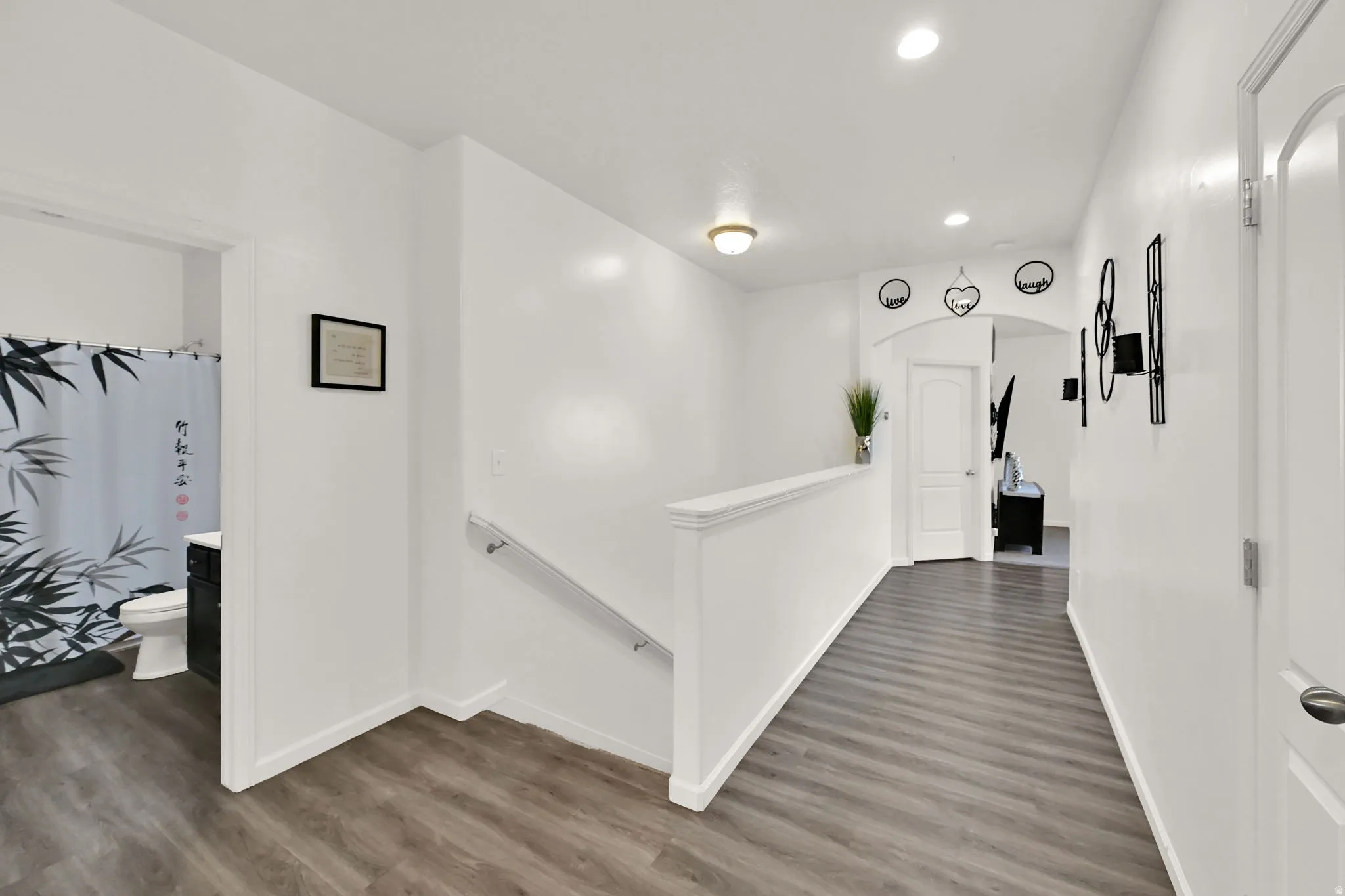 ENTRY FOYER. Wide hallway featuring wood-finish flooring, white walls, recessed lighting, and a white stair railing