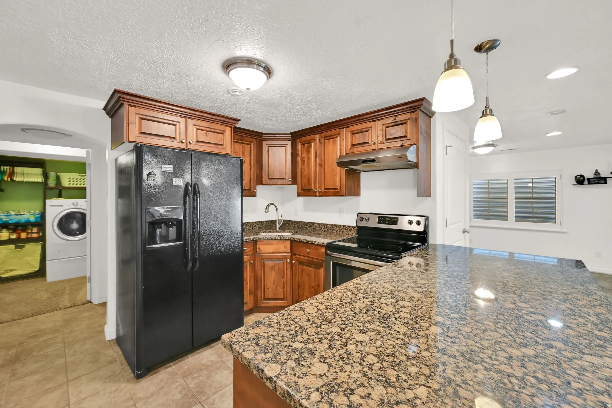 BASEMENT Kitchen featuring wood cabinetry, granite countertops, stainless steel range, and tile flooring