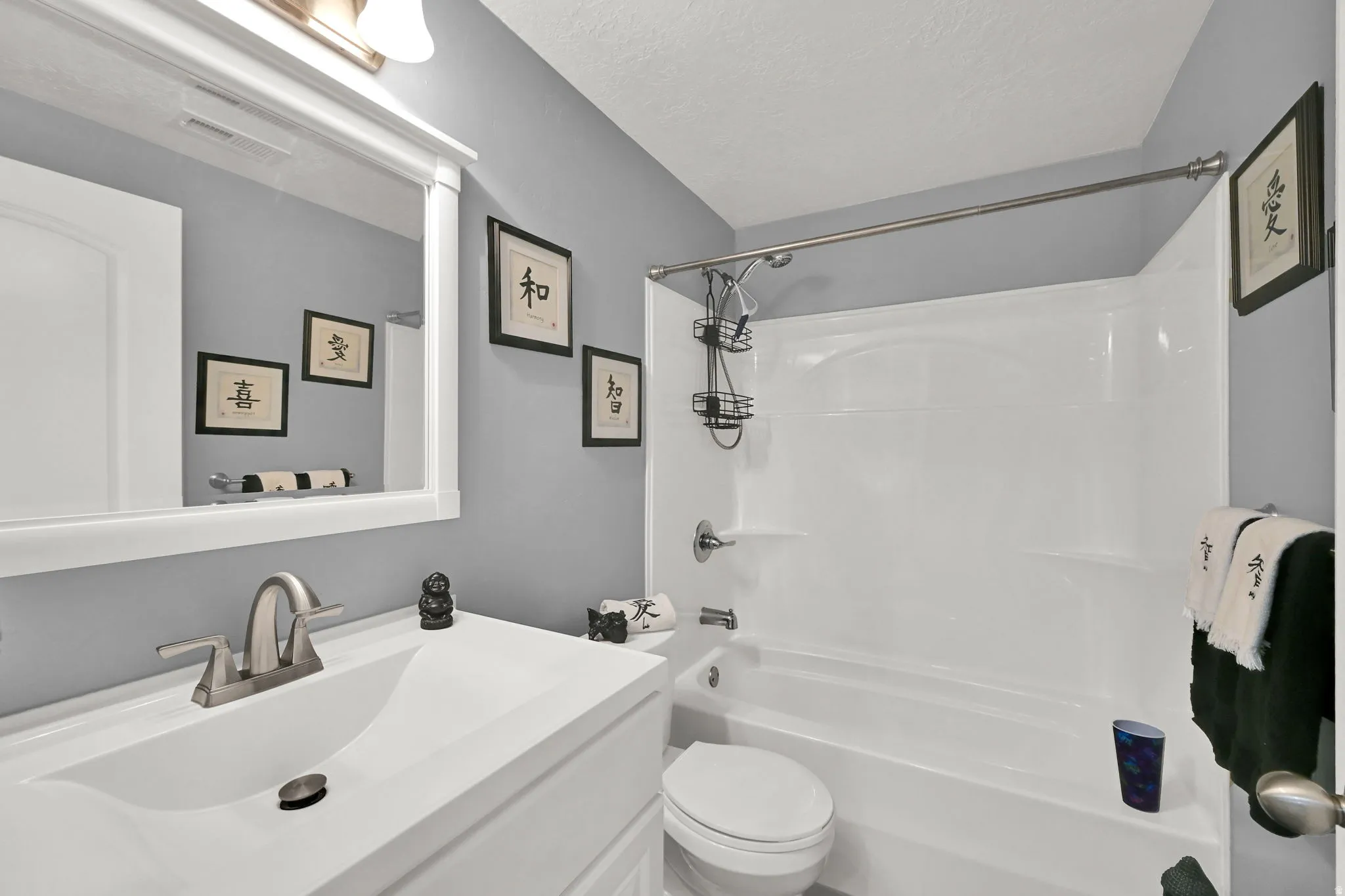 BASEMENT Bathroom featuring a white vanity with an integrated sink, brushed nickel faucet, a framed mirror, and a white tub and shower combination