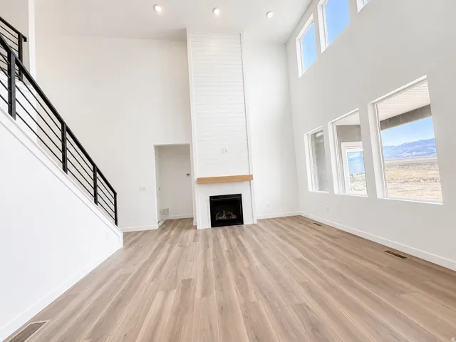 Two-story living area featuring wood-finish flooring, a contemporary fireplace with shiplap surround, and a natural wood mantel