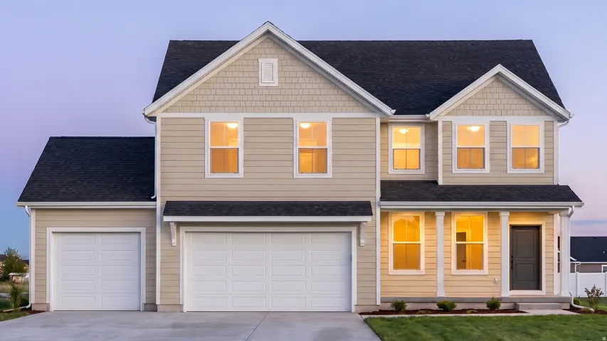 Two-story exterior with light-colored siding, contrasting dark roof, covered entry with white columns, and a two-car garage