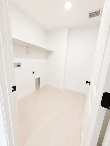 Laundry area featuring tile flooring, a built-in wall shelf, recessed lighting, and a white paneled door with black hardware