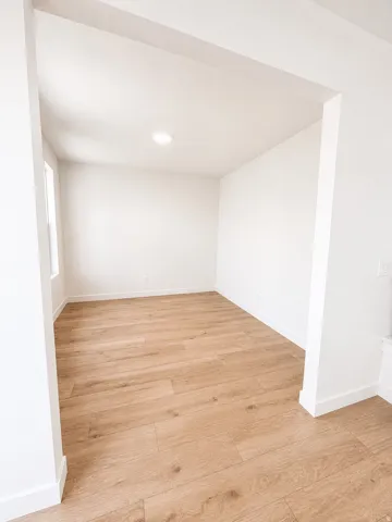 Recessed lighting with wood-finish flooring and white painted walls