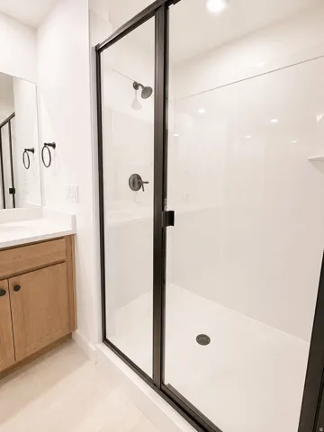 Walk-in shower with clear glass enclosure and matte black fixtures