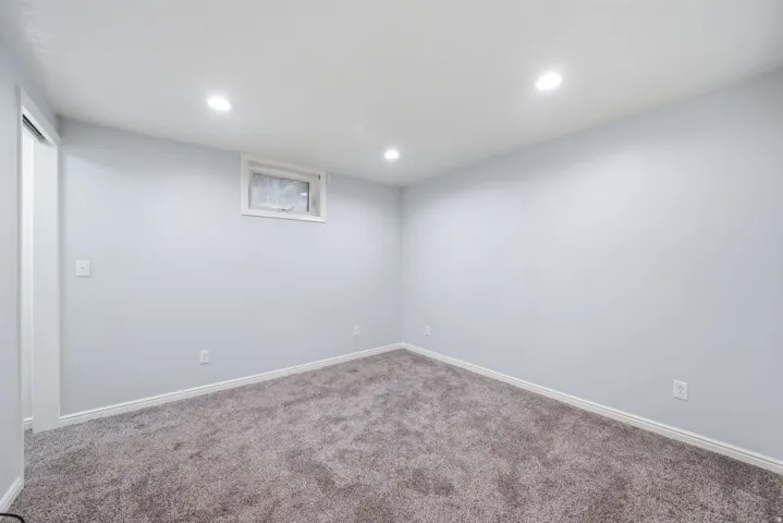 Recessed lighting, light gray walls, white trim, and gray carpet