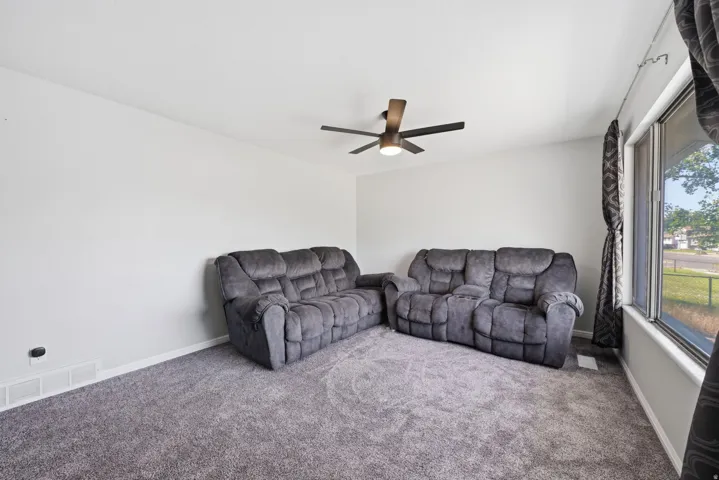 Neutral wall color, wall-to-wall carpeting, and a ceiling fan with integrated lighting