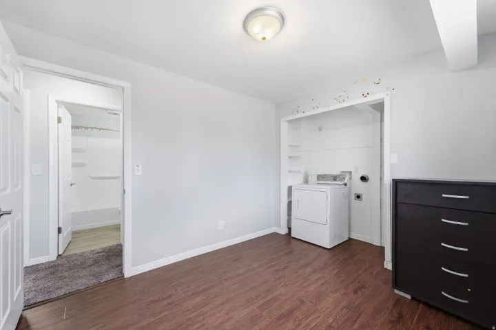 Wood-finish flooring, overhead ceiling light fixture, and a dedicated laundry area with integrated shelving