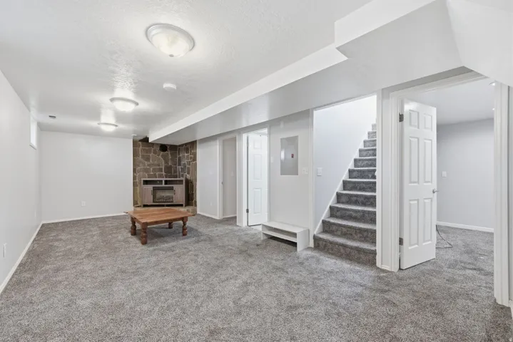 Spacious room featuring gray carpet, stone-faced wall, built-in shelving, and recessed lighting