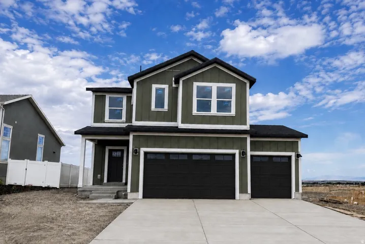 Two-story residence featuring a dark green exterior, white trim, a two-car garage, an additional single-car garage, and a concrete driveway