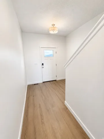 Bright hallway with wood-finish flooring, clean white walls, and recessed ceiling lighting