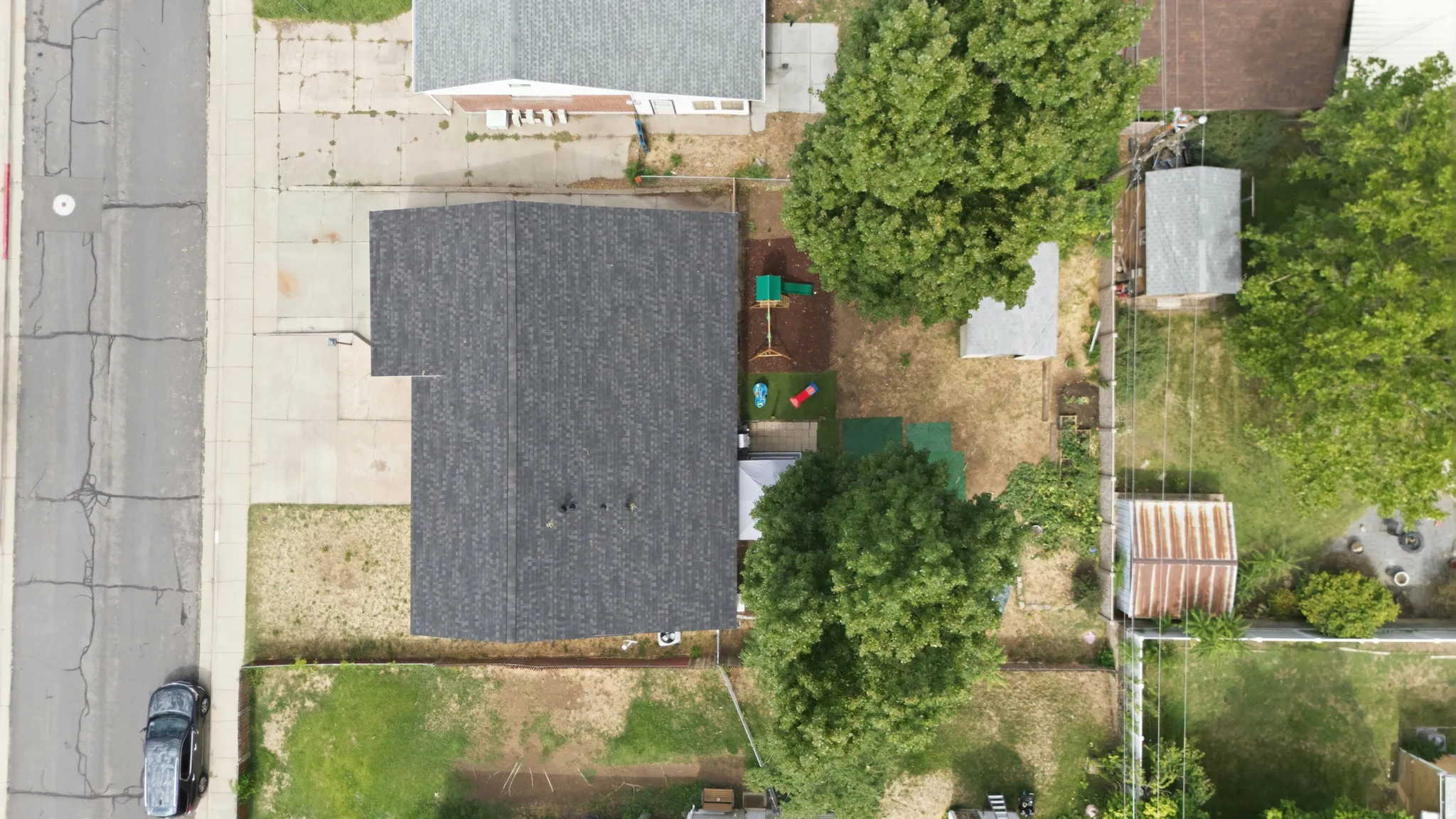 Asphalt shingle roof with a concrete driveway and mature trees