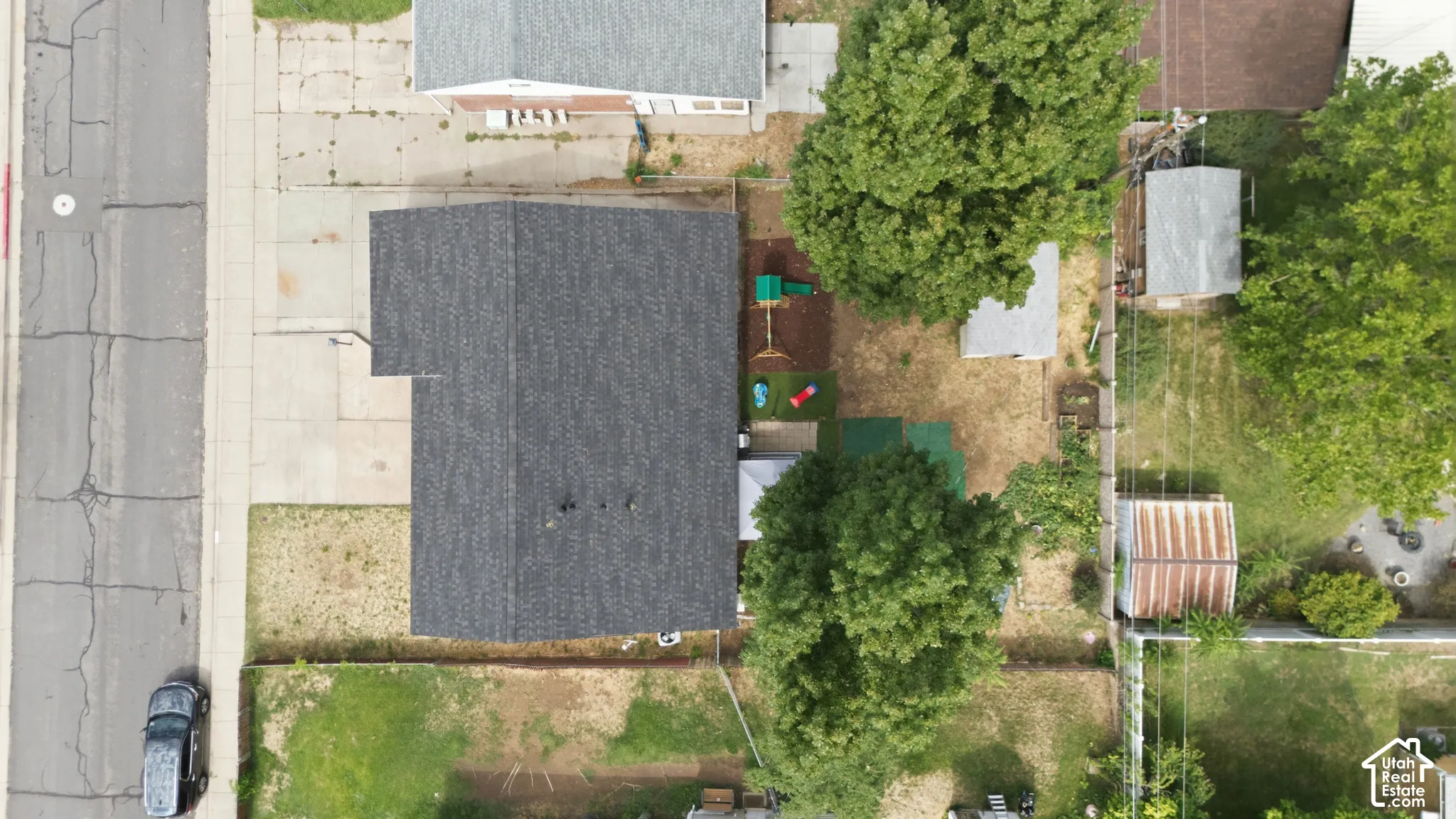 Asphalt shingle roof with a concrete driveway and mature trees