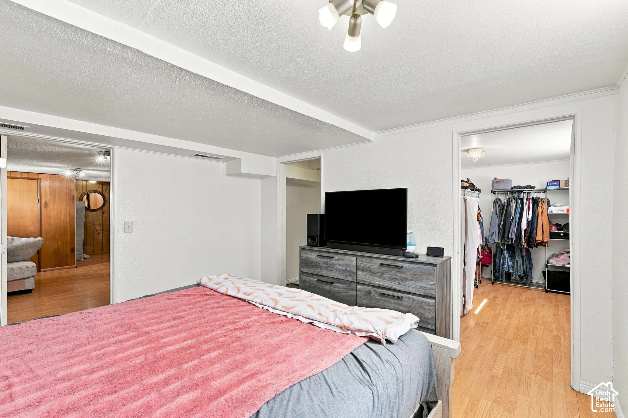 Interior space featuring white walls, light wood-finish flooring, and a multi-bulb flush-mount ceiling fixture