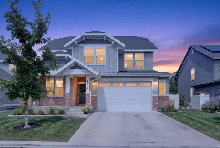Two-story residence featuring brick and siding facade, covered front porch, attached garage, and a concrete driveway