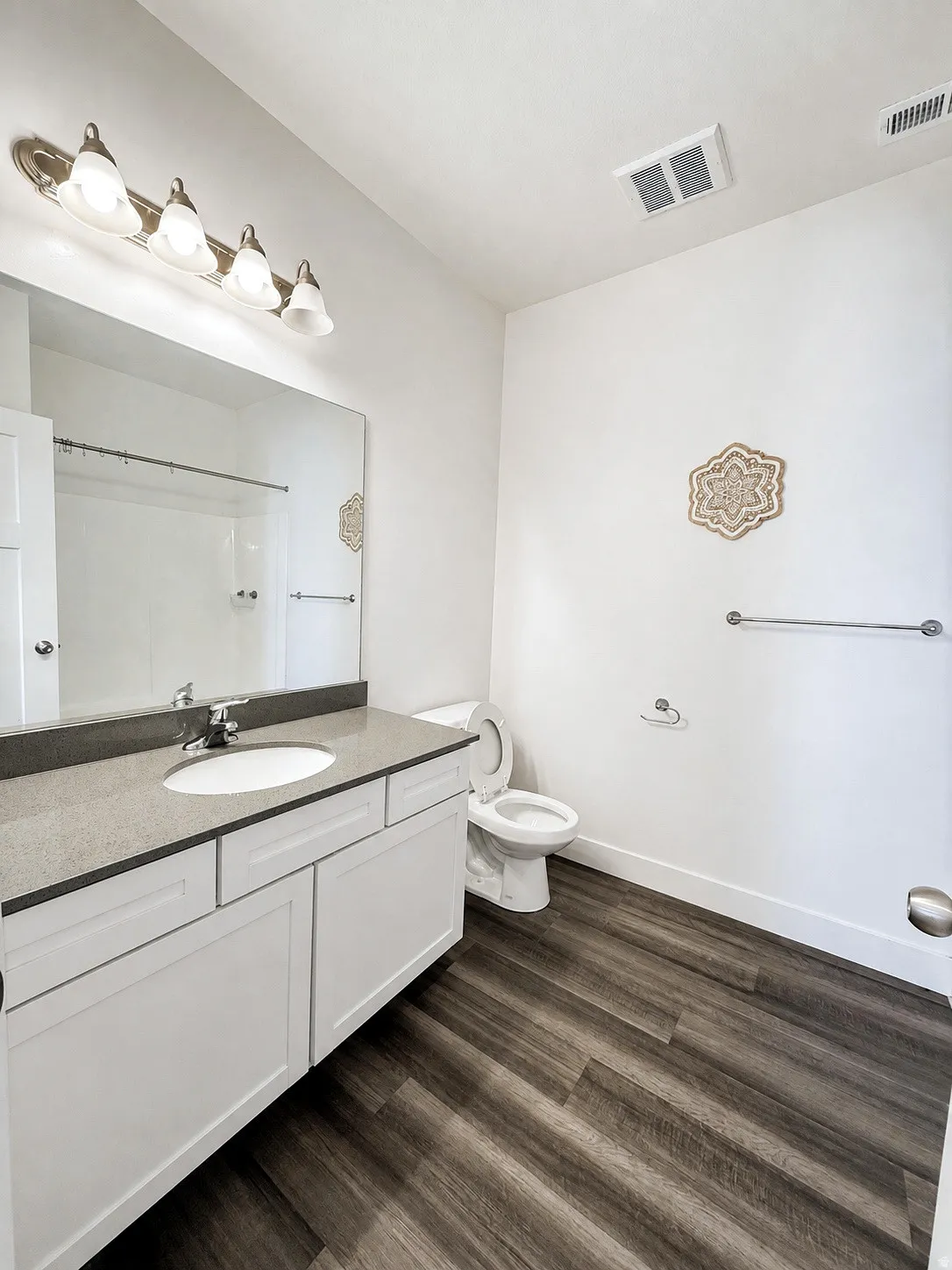 White shaker vanity with a light-toned countertop, undermount sink, and wood-finish flooring