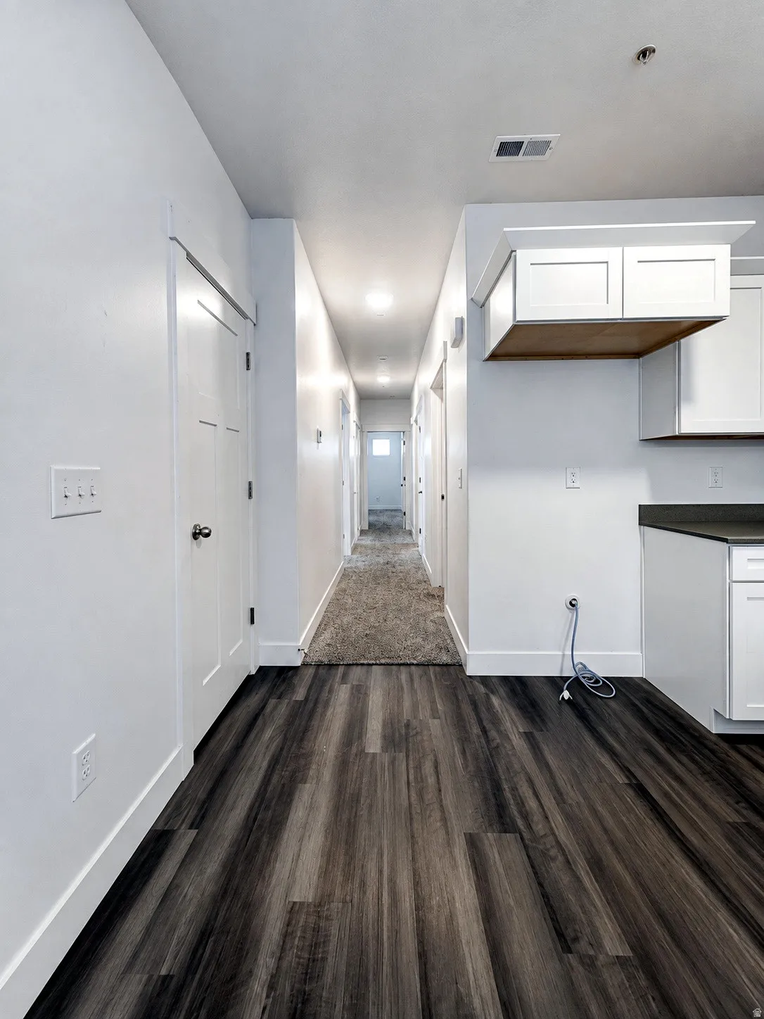 Wood-finish flooring, white walls, white cabinetry, and recessed lighting
