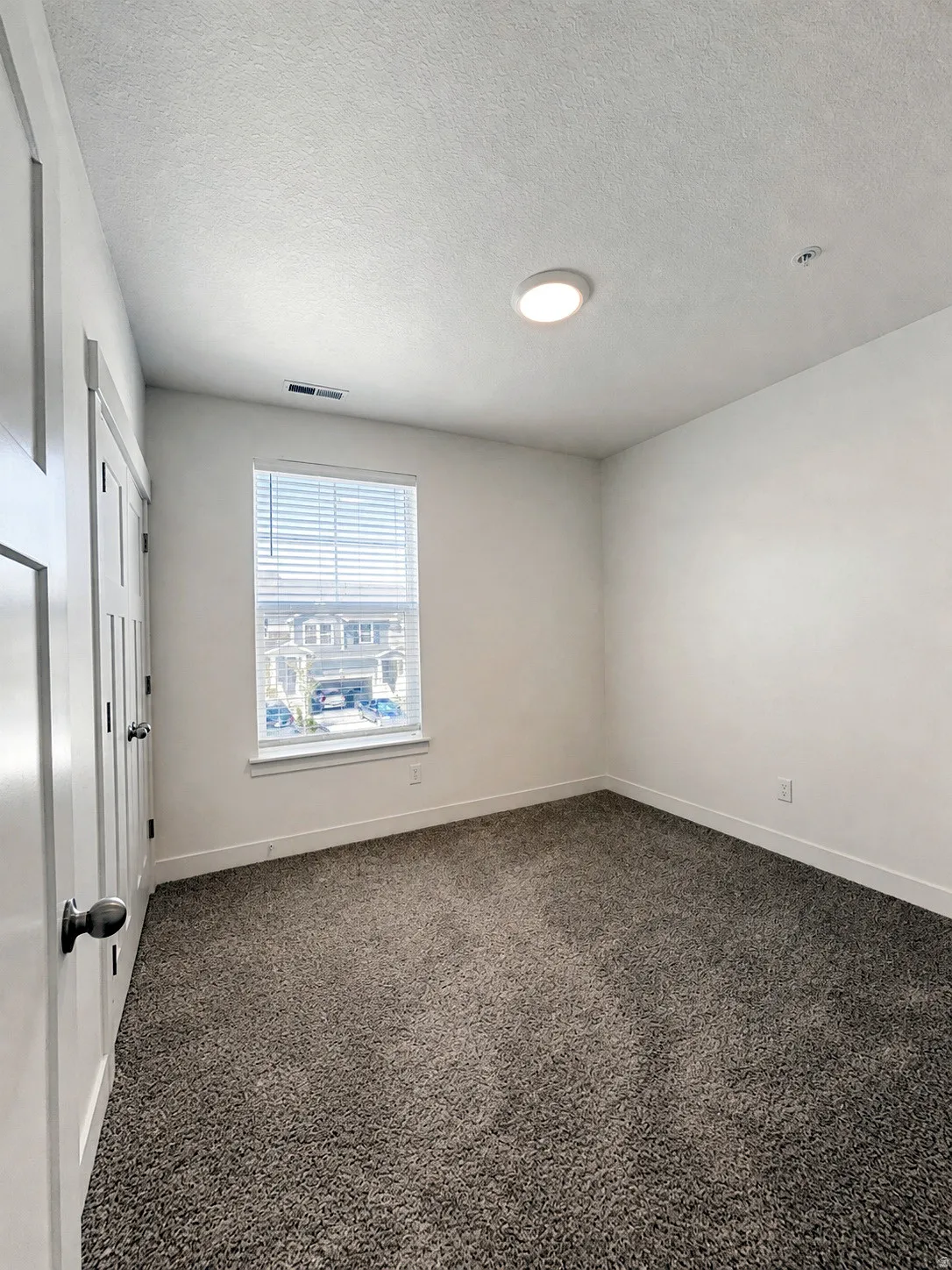 Recessed ceiling light, neutral-toned carpet, and window with blinds