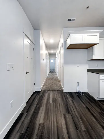Wood-finish flooring, white walls, white cabinetry, and recessed lighting