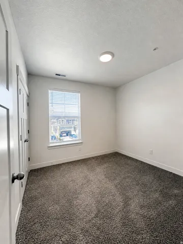 Recessed ceiling light, neutral-toned carpet, and window with blinds