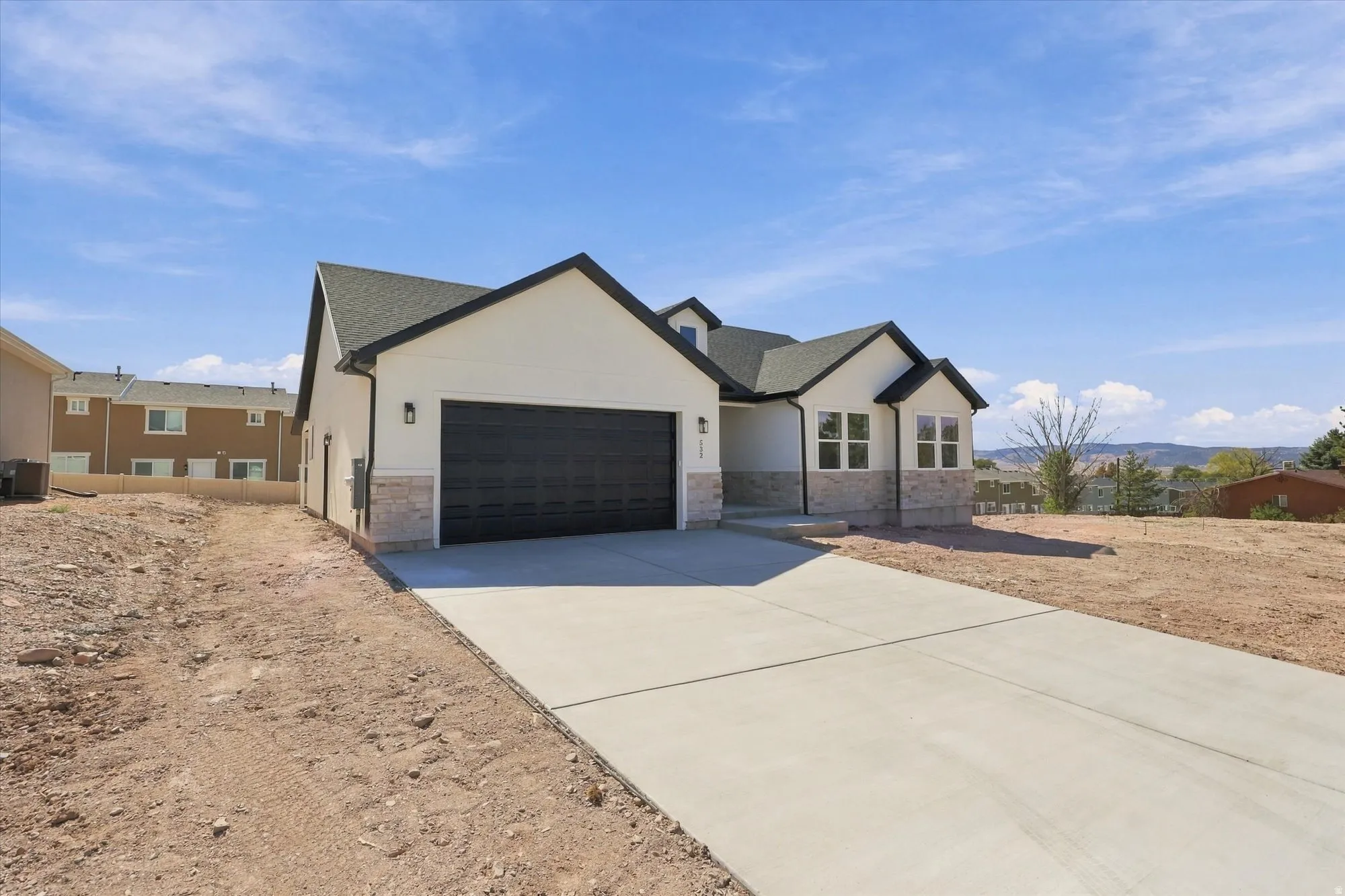 Contemporary exterior with a dark-pitched roof, white siding, and stone accents