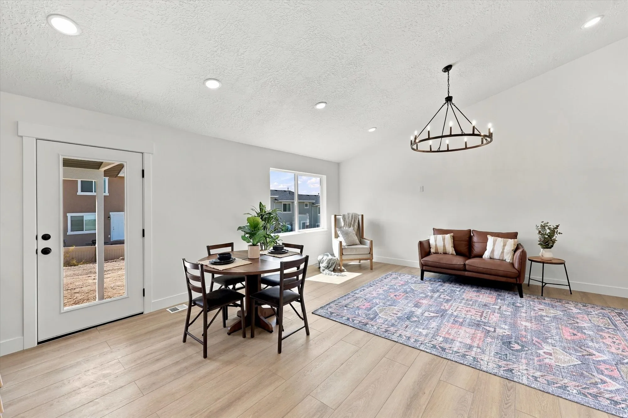 Vaulted ceiling with a contemporary chandelier and recessed lighting, wood-finish flooring, white walls, and a glass-paneled exterior door