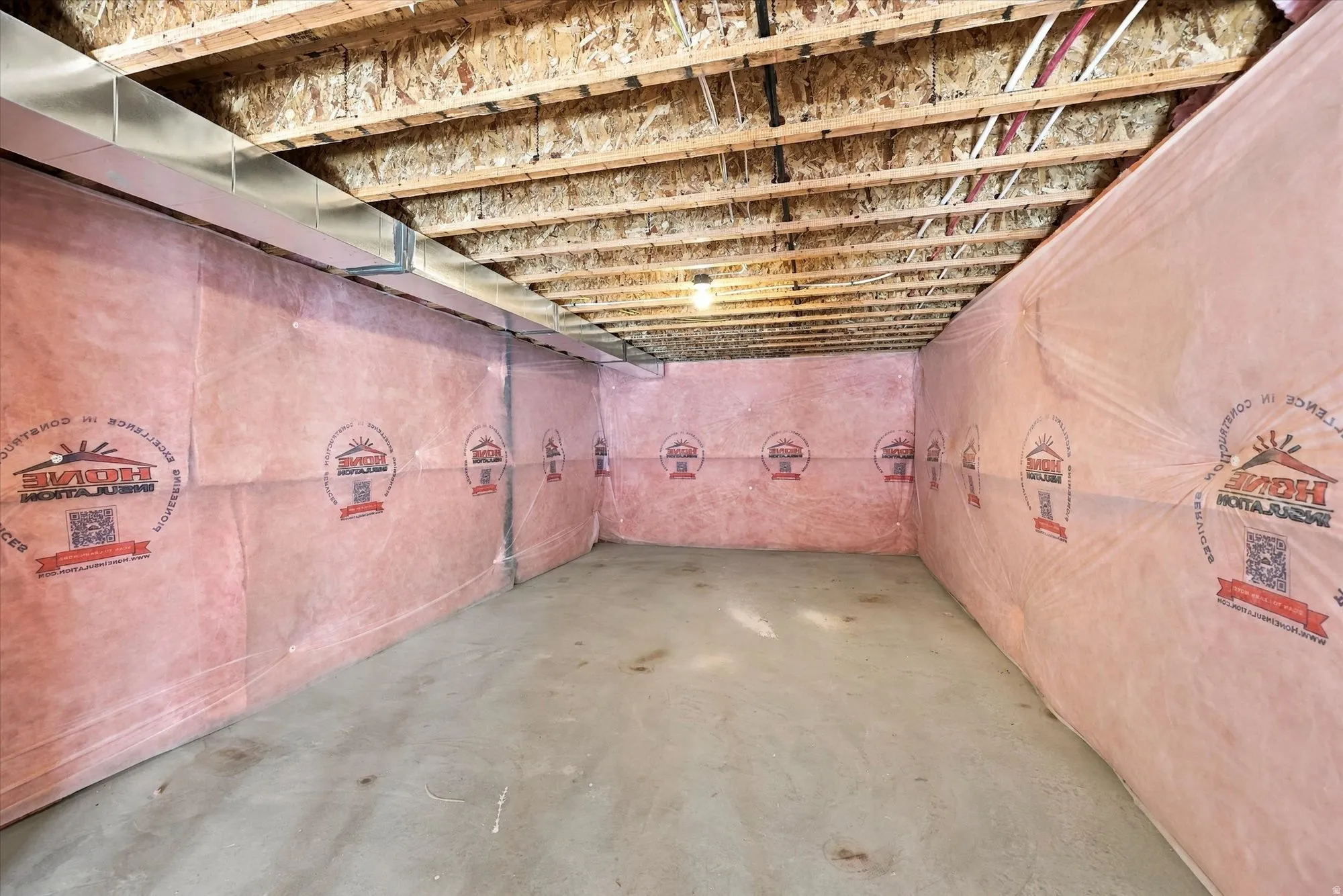 Unfinished basement with concrete flooring, insulated walls, exposed ceiling joists, and visible ductwork