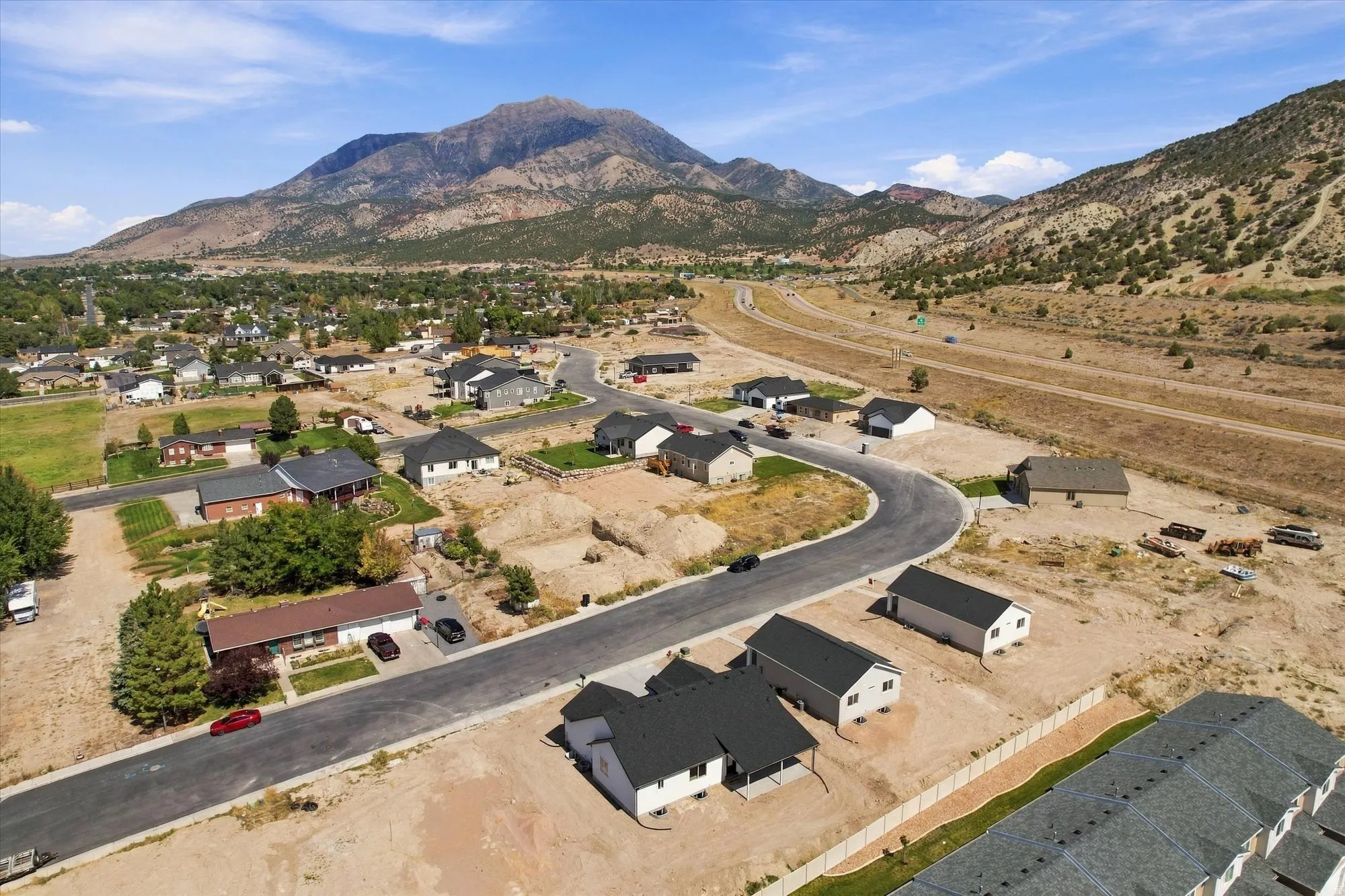 Residential area with established homes and new construction sites, surrounded by mountainous terrain