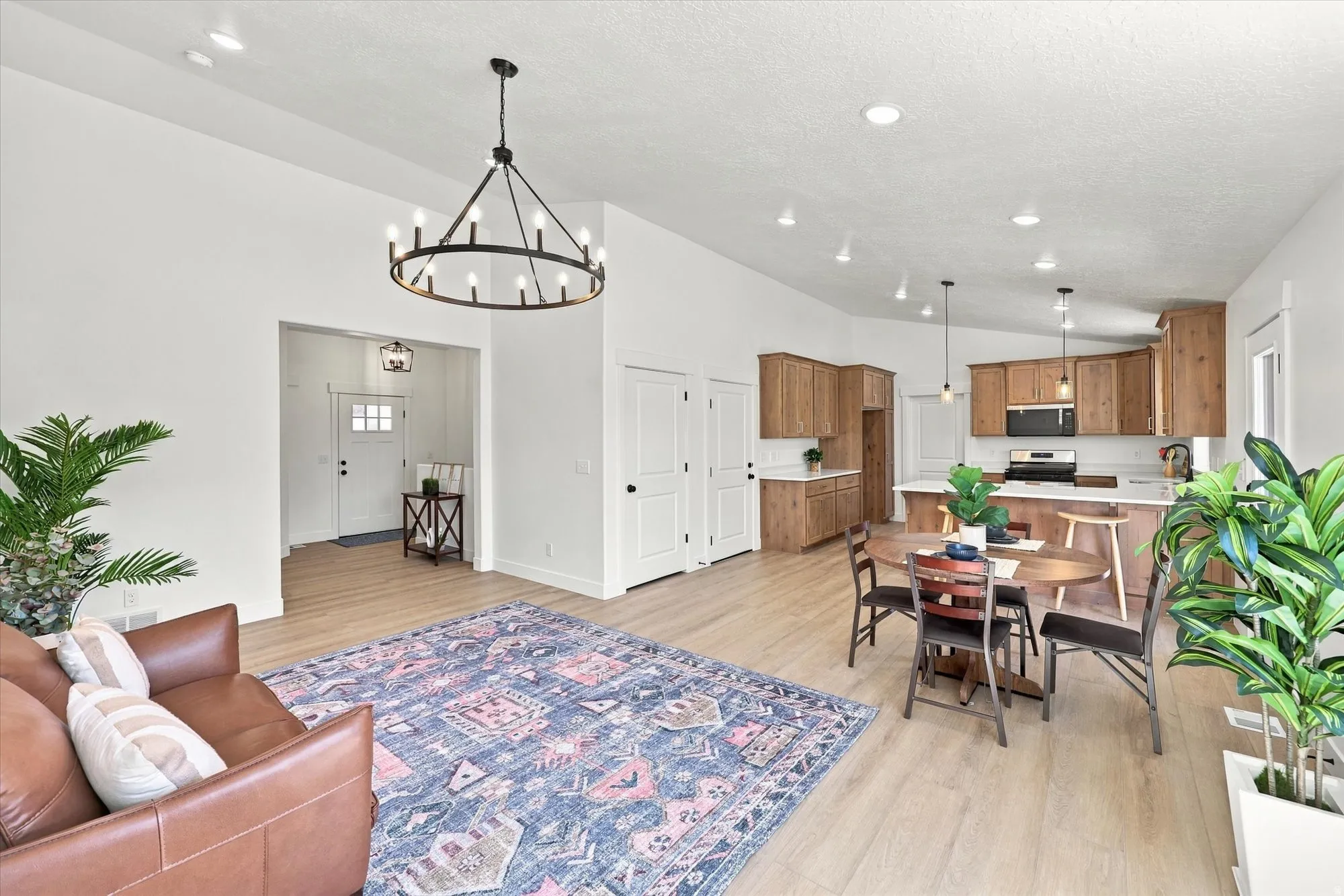Open-concept living space featuring wood-finish flooring, a contemporary chandelier, recessed lighting, and a kitchen with wood cabinetry and a white countertop