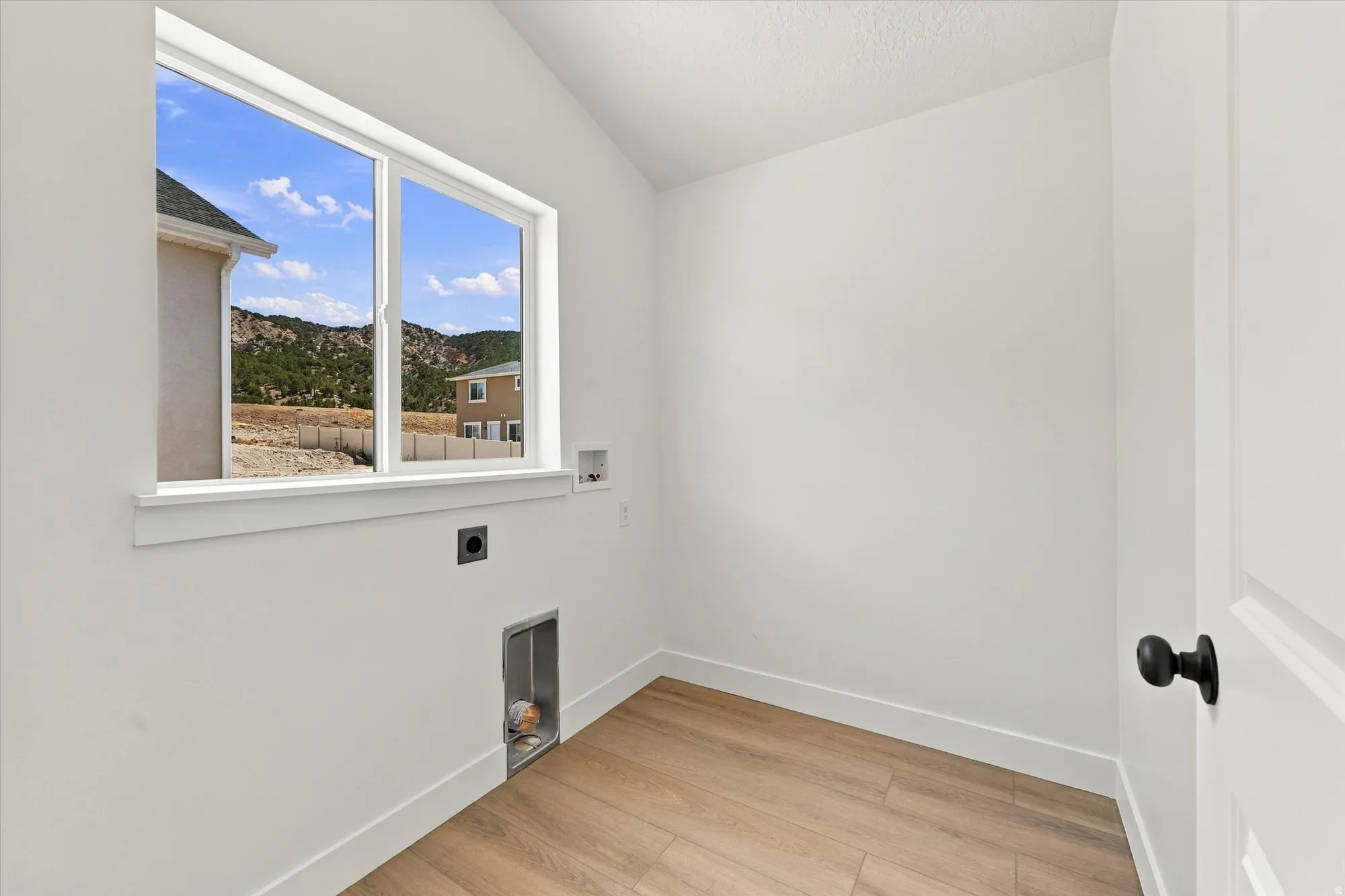 Laundry area with wood-finish flooring, white walls, and a window offering a mountain backdrop